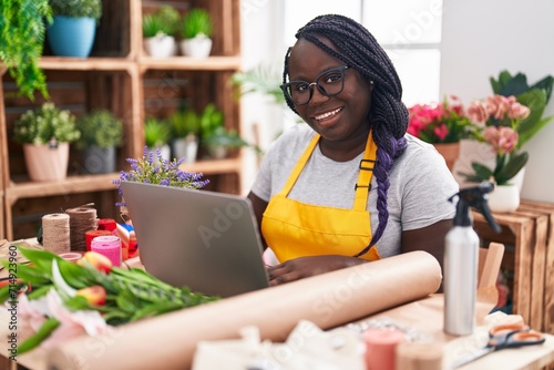 African american woman florist smiling confident using laptop at florist