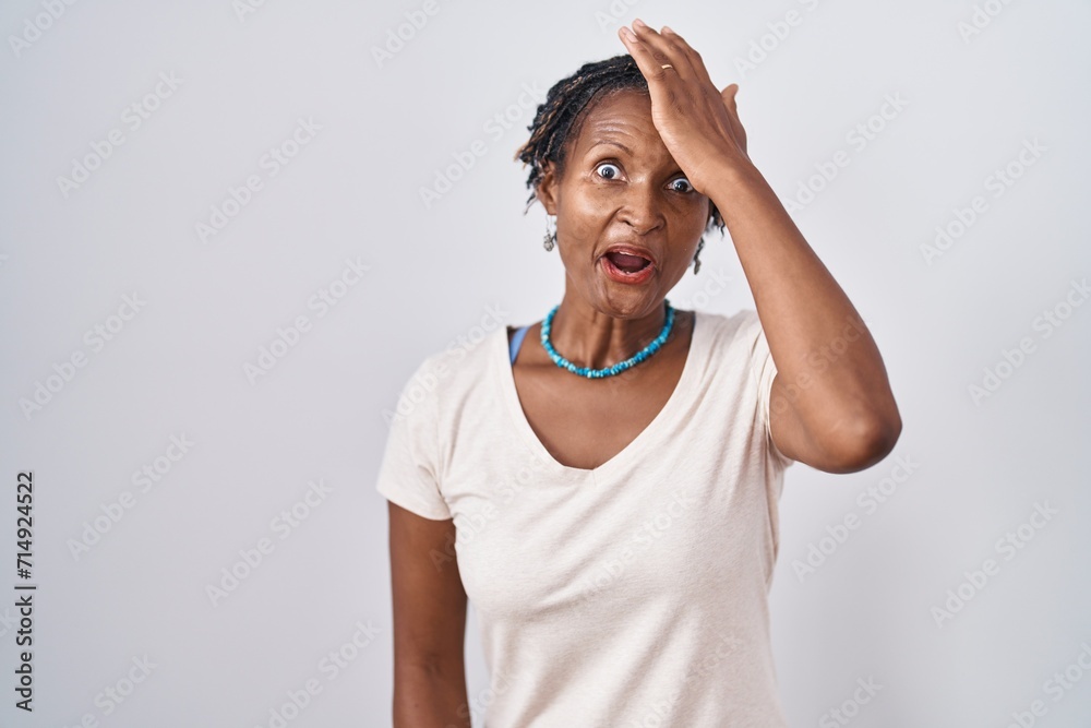 African woman with dreadlocks standing over white background surprised with hand on head for mistake, remember error. forgot, bad memory concept. African woman with dreadlocks standing over white background surprised with hand on head for mistake, remember error. forgot, bad memory concept.