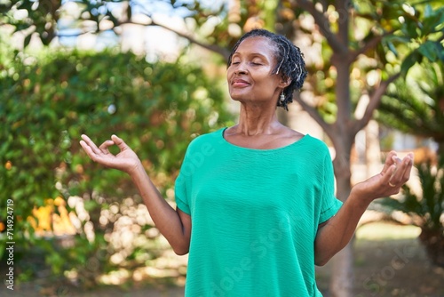 Middle age african american woman smiling confident doing yoga exercise at park