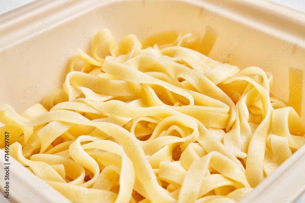 Close-up of fresh fettuccine pasta in a white container highlighting italian cuisine and homemade cooking.