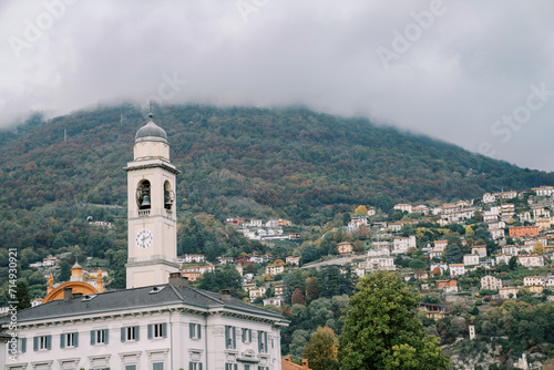 High bell tower near an ancient villa in the town of Cernobbio at the foot of the mountains. Como, Italy