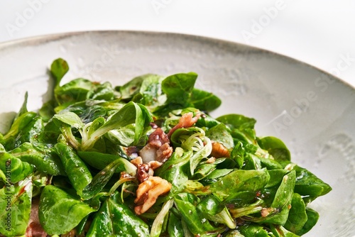 Foto Closeup of a fresh mache salad with walnuts and vinaigrette dressing served on a ceramic plate