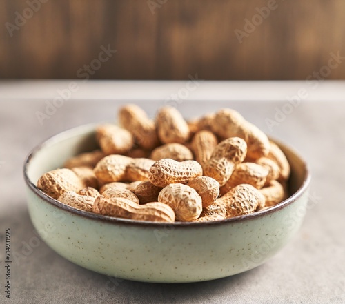 A bowl full of unshelled peanuts on a wooden table, suggesting a natural, healthy snack.