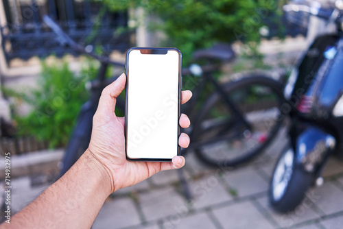 Man holding smartphone showing white blank screen at bike parking