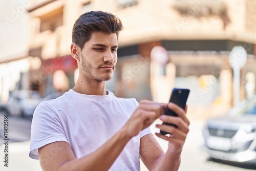 Young hispanic man using smartphone with serious expression at park