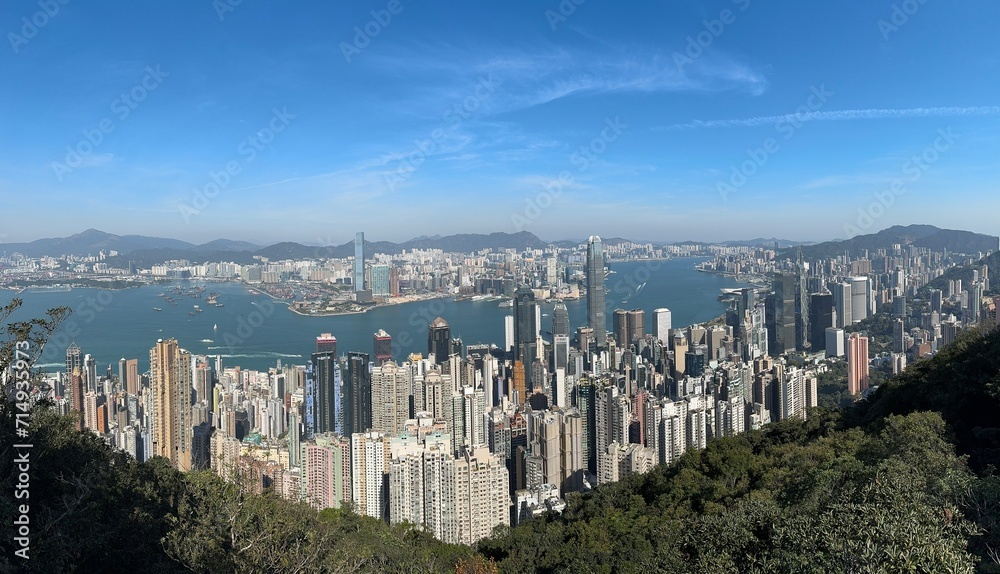 View of Hong Kong from The Peak. The Peak or Victoria Peak is a summit of a hill located at Hong Kong Island overlooking the skyscrapers of Hong Kong and Victoria Harbor from a height. Aerial view.