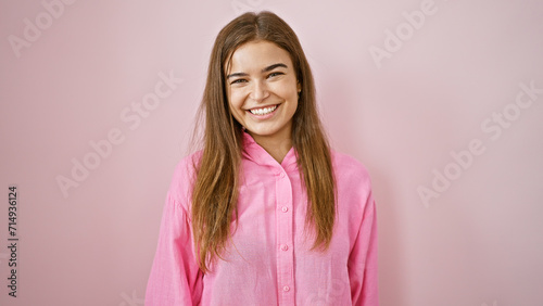 Attractive  confident young hispanic woman smiling cheerfully over isolated pink background. she s standing casually  her hairstyle looking cool and full of joy.