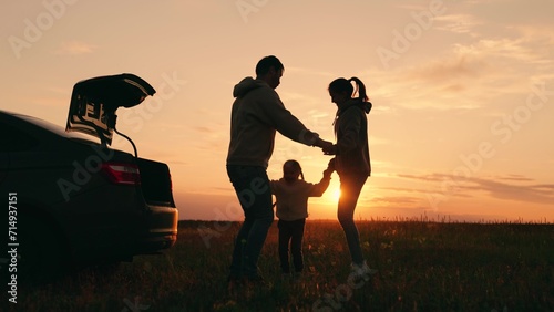 Dad with child  daughter  mother  child play  dance together against backdrop of sunset next to car. Happy family traveling by car. Parents child stopped at campsite by car. Family picnic in nature