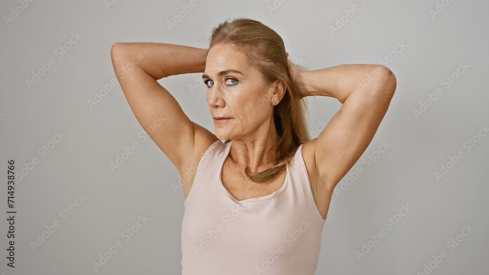 A mature, blonde woman posing confidently against a white background, evoking a sense of elegance and strength. A mature, blonde woman posing confidently against a white background, evoking a sense of elegance and strength.