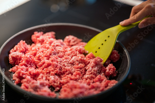 stirring mince meat in frying pan.