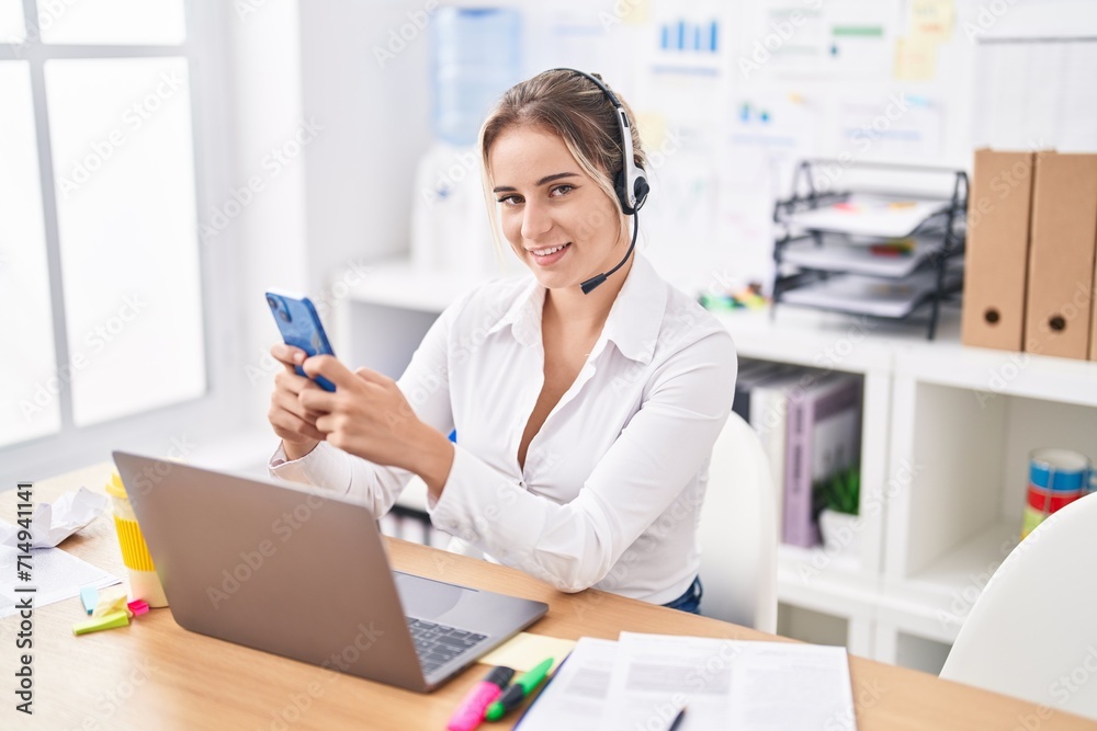 Young blonde woman call center agent holding using smartphone working at office
