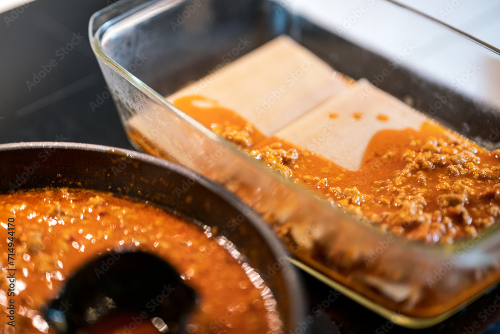 making lasagna, adding pasta to mince meat in ovenproof dish. making lasagna, adding pasta to mince meat in ovenproof dish.