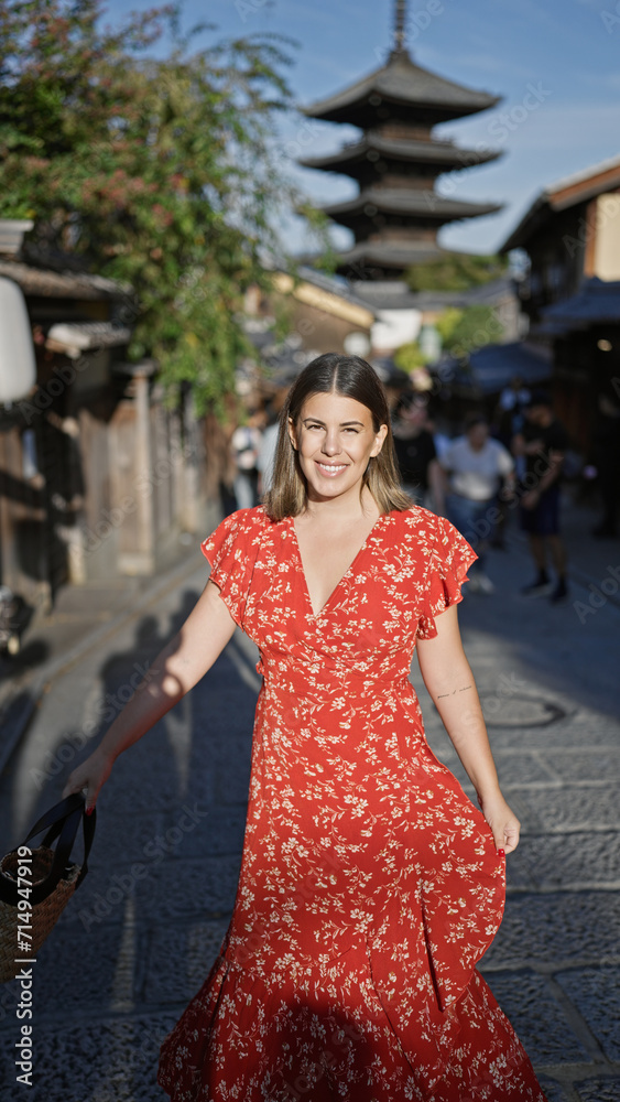 Spinning around in joy, a beautiful hispanic woman unveils her dress on the ancient streets of gion, kyoto, her radiant smile adding charm to this mesmerizing japanese old town.