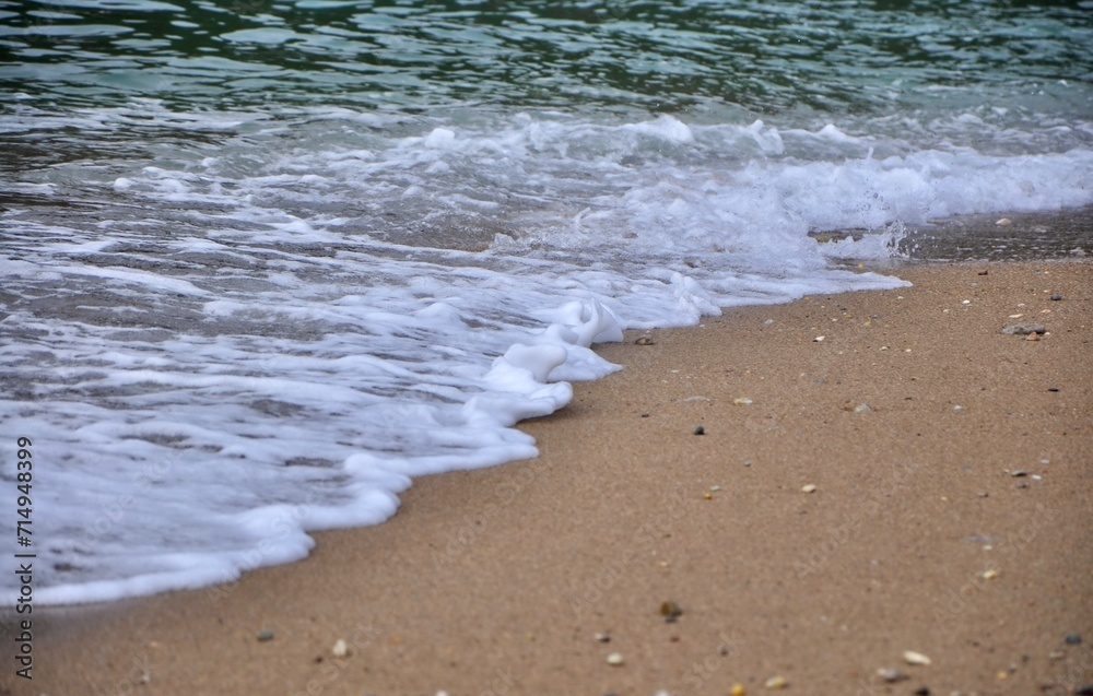 Sea sandy shore with an oncoming foam wave. Travel and tourism. Natural summer background. A foaming wave comes to the sand beach like a high tide Sea sandy shore with an oncoming foam wave. Travel and tourism. Natural summer background. A foaming wave comes to the sand beach like a high tide