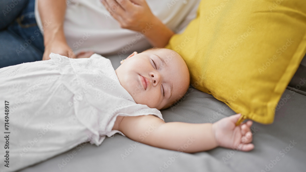 Exhausted mother lying on bed, lovingly watchful while her baby daughter sleeps in bedroom amidst the wholesome family background in their indoor home.