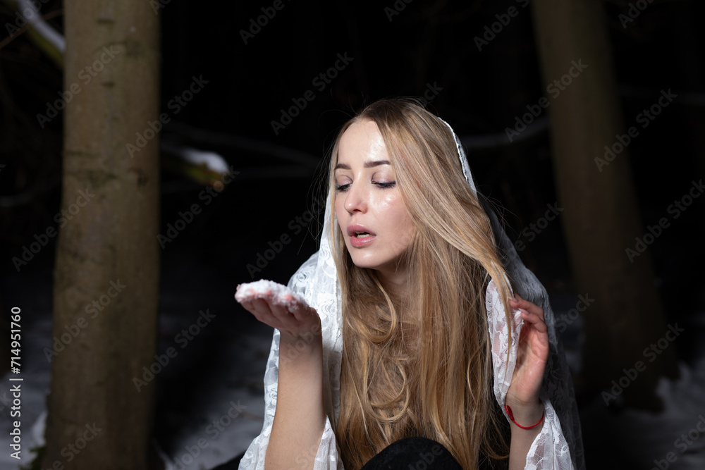Fototapeta premium young blond woman with blue eyes dancing in the dark night of an very cold snow winter