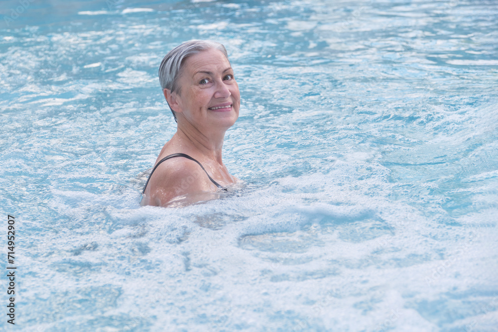 Senior caucasian woman with gray short wet hair enjoying in outdoor thermal swimming pool. Senior caucasian woman with gray short wet hair enjoying in outdoor thermal swimming pool.