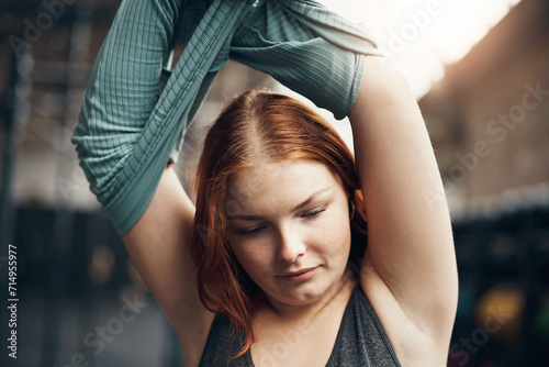 Young woman taking off a shirt before a workout at the gym photo