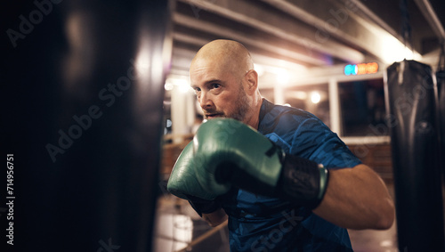 Mature man exercising with a punching bag in a boxing gym photo