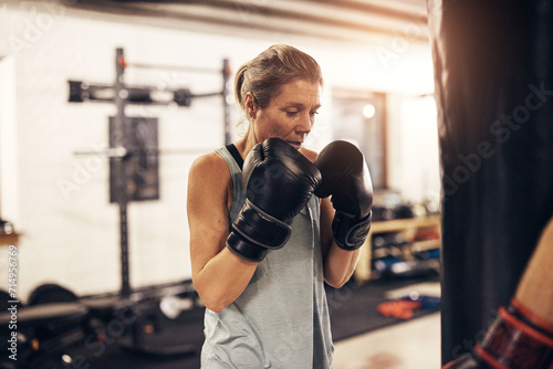 Fit mature women working out on a gym punching bag photo