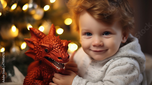one year old baby with red hair received red dragon toy as a Christmas gift, a symbol of 2024 © Ekaterina