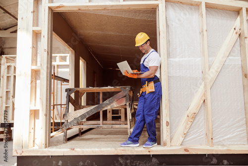 Cheerful male builder using laptop at construction site
