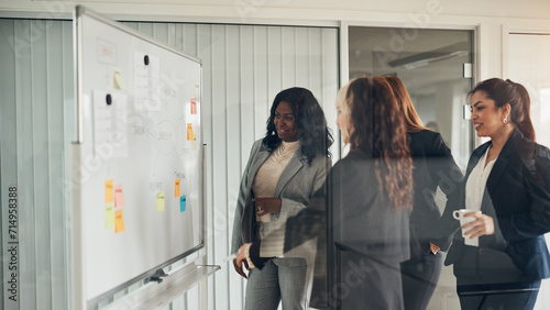 Smiling businesswomen brainstorming together on a whiteboard in an office photo