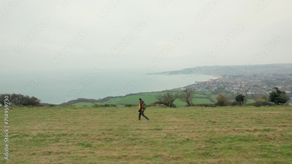 Hiker walking outdoor on the hill near The Obelisk, Swanage, Dorset, England. Overcast day winter. Hiker walking outdoor on the hill near The Obelisk, Swanage, Dorset, England. Overcast day winter.