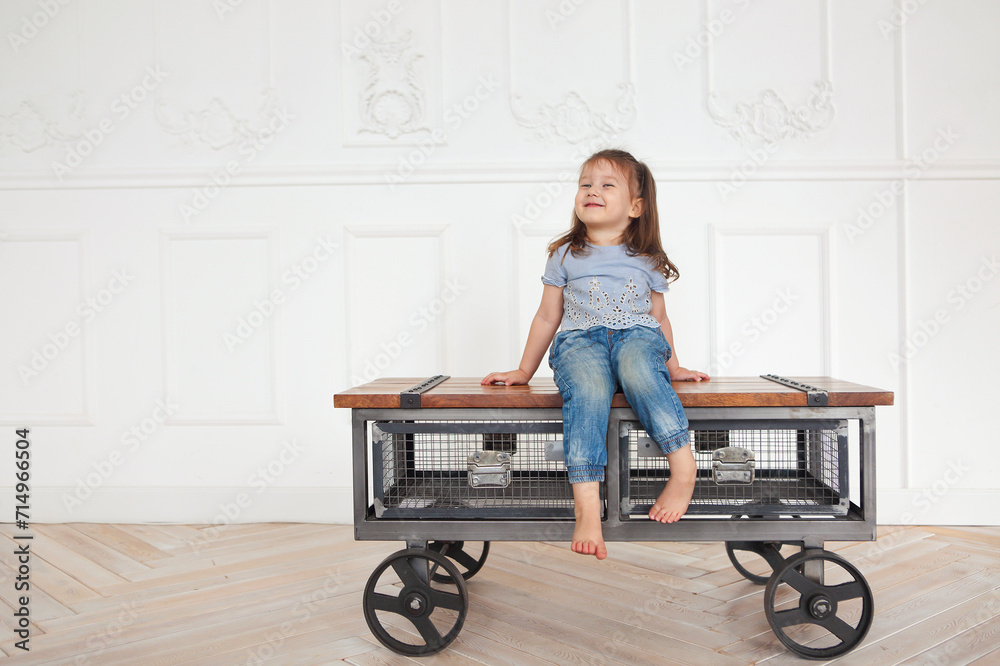 Cute little redhaired girl with blue eyes in denim jeans and blue shirt in a light room Cute little redhaired girl with blue eyes in denim jeans and blue shirt in a light room