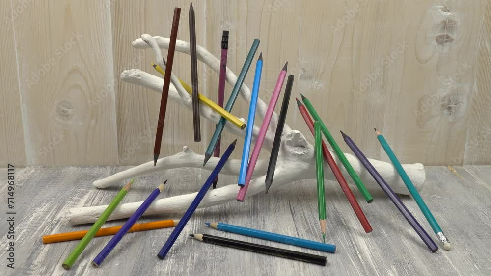 White decorative stand made of tree branch among the colored wood pencils against the background of wooden boards