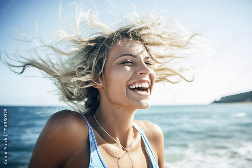 A smiling woman with windblown hair by the sea, wearing a blue top and necklace, conveys freedom under bright sunlight, ai generative
