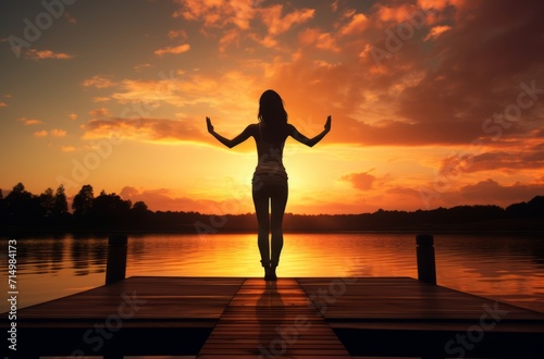 Inspiring silhouette of a woman on a dock at sunset, embracing life, meditative and peaceful.