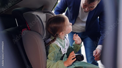 man unfastens seat belt. get child car. leather rear seats. child safety car traveling. car happy family. parent with child lead daughter girl car. happy family concept. Kid schoolgirl loves father. photo