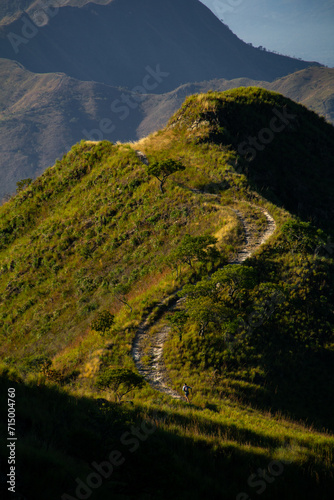 mountain runner going uphill at distance photo