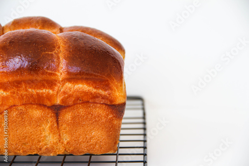 Delicious brioche bread on a black cooling rack right after baking, on a white background. Classical French yeast bread.