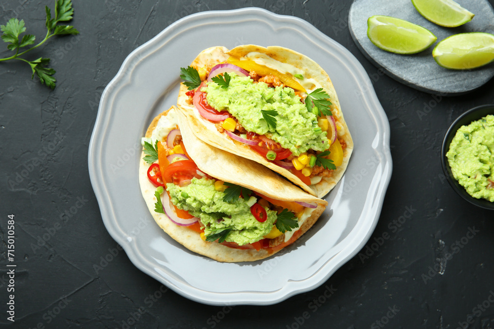 Delicious tacos with guacamole and vegetables served on black table, flat lay Delicious tacos with guacamole and vegetables served on black table, flat lay