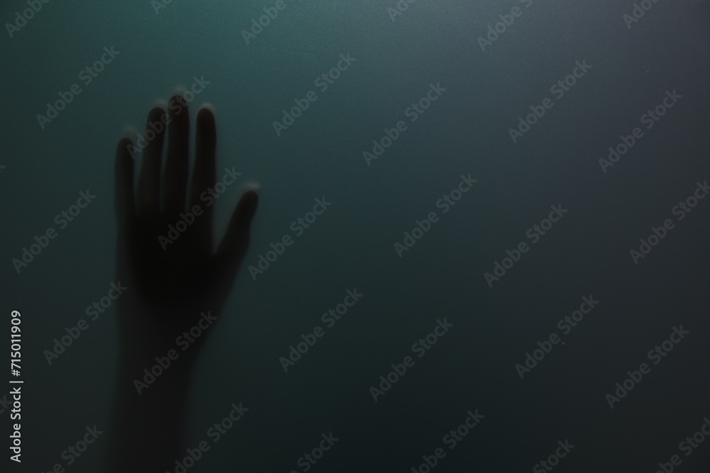 Silhouette of creepy ghost behind glass against color background, closeup. Space for text