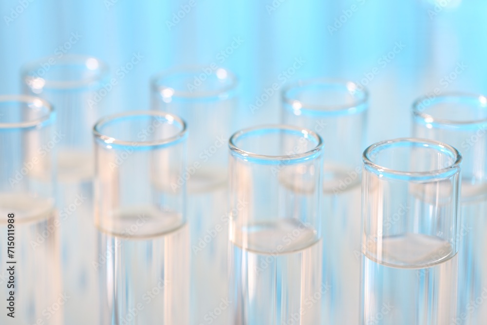 Laboratory analysis. Many glass test tubes on light blue background, closeup Laboratory analysis. Many glass test tubes on light blue background, closeup