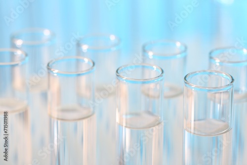 Laboratory analysis. Many glass test tubes on light blue background, closeup