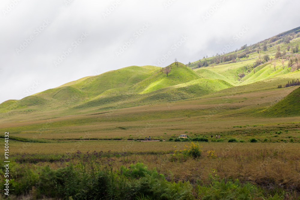 Landscape of green hills in the mountains on a cloudy day. Location of Mount Bromo in Bromo Tengger Semeru National Park, East Java, Indonesia
