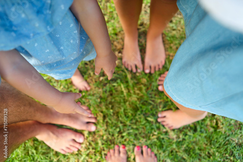 Happy young family spending time outdoor on a summer day. Feet on the grass