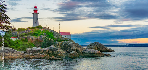Lighthouse on a rocky coast during a cloudy sunset.
