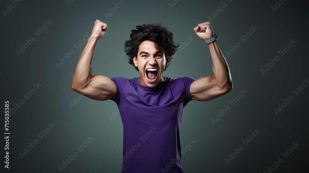 Young man with his fists raised in a victorious gesture, and a broad, joyful smile on his face, likely celebrating a success or win. Young man with his fists raised in a victorious gesture, and a broad, joyful smile on his face, likely celebrating a success or win.