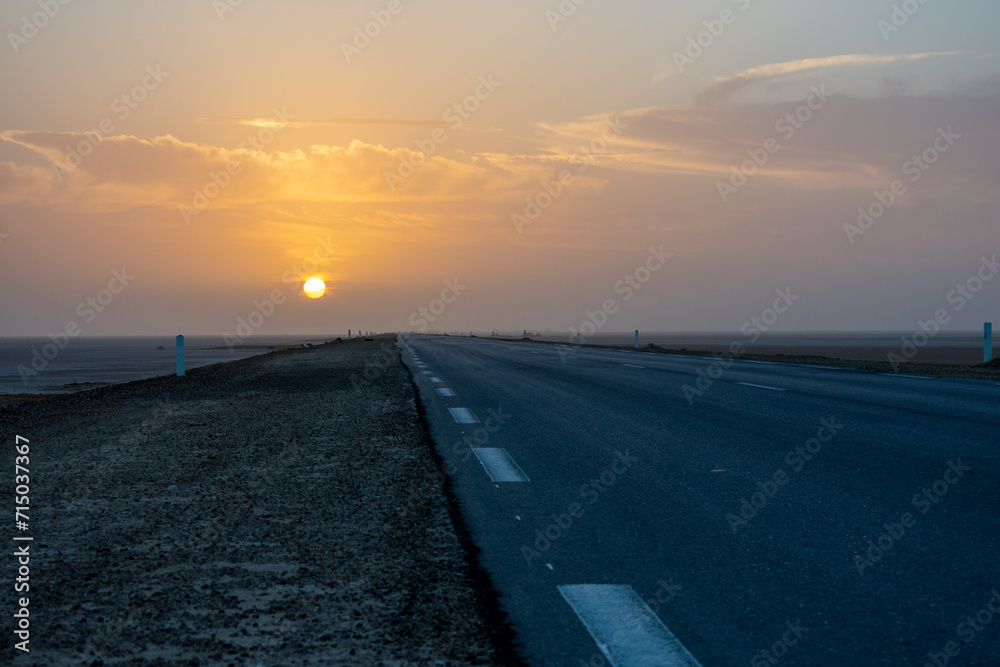 Beautiful colourful sunset over endless empty road in middle of desert. Asphalt highway in Tunisia, North Africa.