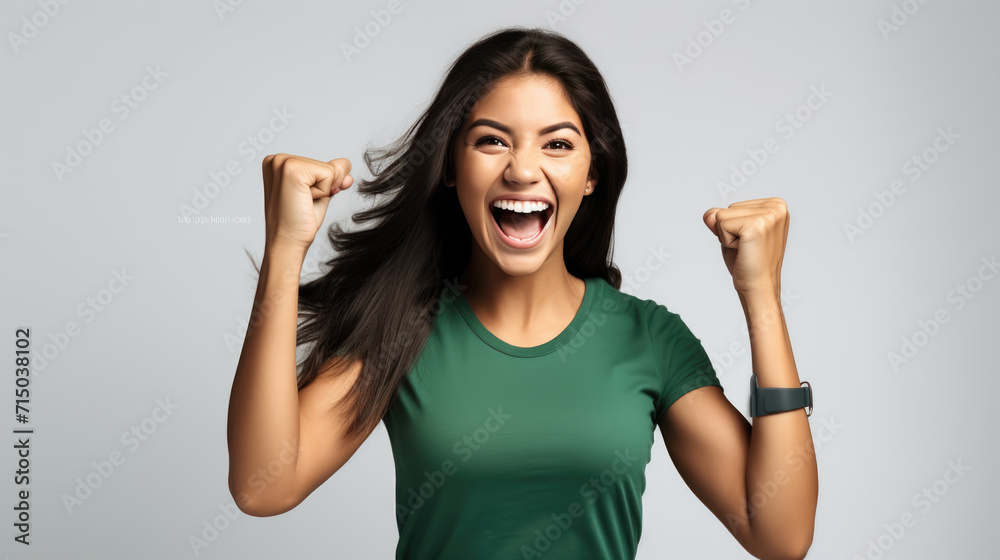 Exuberant young woman with her fists raised in a victorious gesture, and a broad, joyful smile on her face, likely celebrating a success or win. Exuberant young woman with her fists raised in a victorious gesture, and a broad, joyful smile on her face, likely celebrating a success or win.