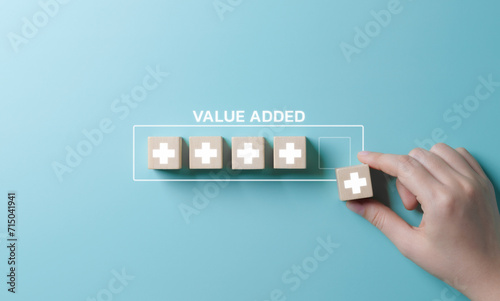 Value add concept. Hand place wooden cube with plus sign on light blue background. Positive thinking or personal growth and development. download style which means value added. value add for business. photo