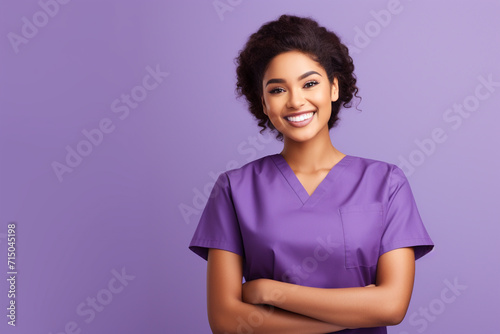 Attractive woman wearing medical scrubs isolated on purple background
