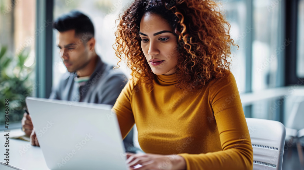 Young woman is focused on working on her laptop in a modern office