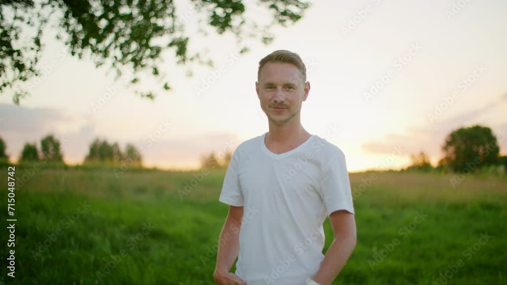 Portrait of Young Caucasian Blond Man looking to camera and smiling outdoors with nature landscape. Medium hero shot of confident Guy in white t-shirt. 4K orbit video with copy space in slow motion Portrait of Young Caucasian Blond Man looking to camera and smiling outdoors with nature landscape. Medium hero shot of confident Guy in white t-shirt. 4K orbit video with copy space in slow motion