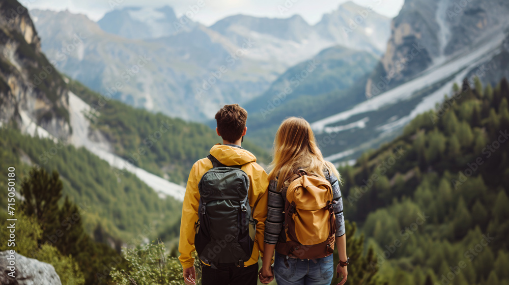 Two hikers looking at mountain scenery from a high vantage point. Exploration and travel concept with nature view
